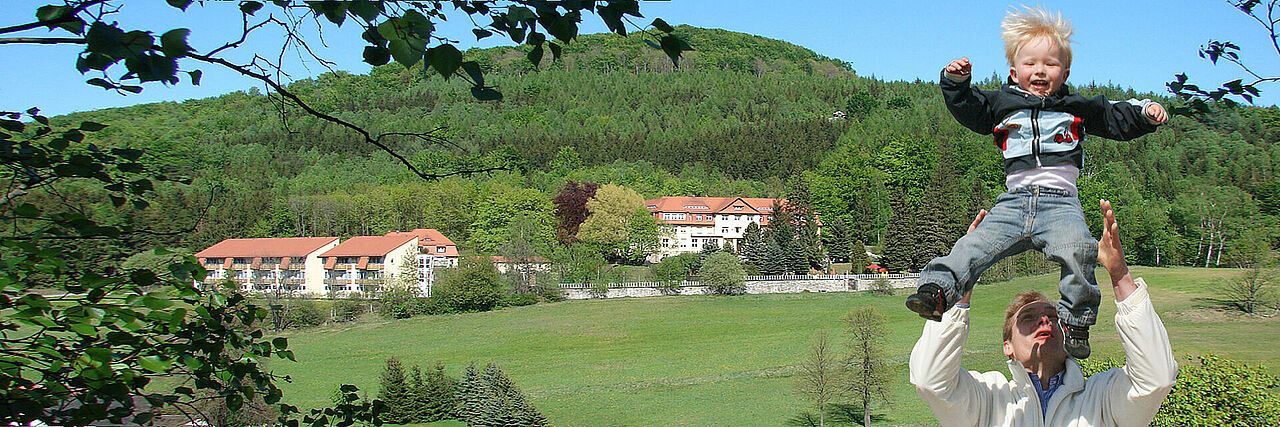 Vater wirft Kind in die Luft, Kurheim im Hintergrund