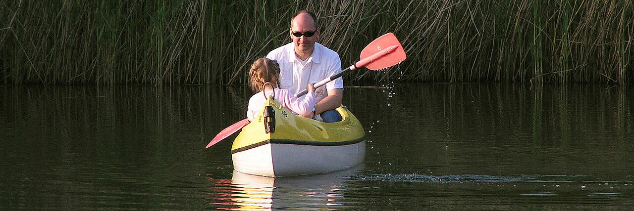 Vater paddelt mit Kind im Kanu